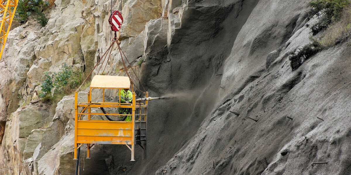 worker in crane vehicle sprayed concrete , shotcrete,on the highway slope  for prevent the collapse